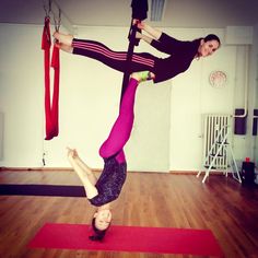 two women doing aerial acrobatic exercises in a room