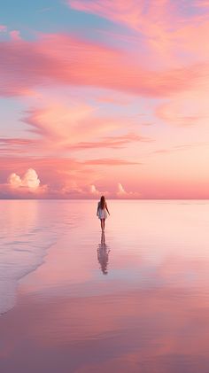 a woman walking on the beach at sunset