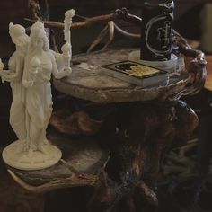 a statue is sitting on top of a table next to a book and candle holder