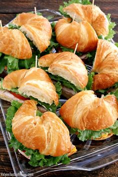 sandwiches with toothpicks are arranged on a clear plate, ready to be eaten