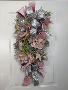 a pink and silver wreath hanging on the front door