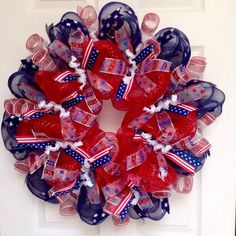 a red, white and blue mesh wreath with american flag decorations on the front door