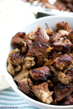 a white bowl filled with meat sitting on top of a table