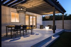 an outdoor dining area is lit up at night with lights shining on the table and chairs