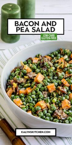 a white bowl filled with peas, carrots and pea salad next to two candles