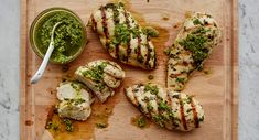 grilled chicken with pesto sauce on a cutting board