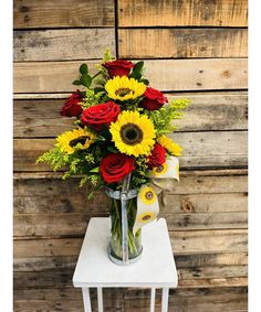 a vase filled with red roses and yellow sunflowers