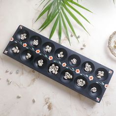 there is a black tray that has nine cups in it and flowers on the side