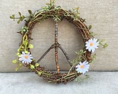 a peace sign made out of twigs and flowers on a couch with a pillow in the background