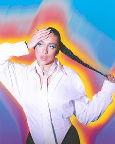 a woman in white shirt holding her hair up to her head with one hand on top of her head