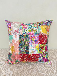 a colorful patchwork pillow sitting on top of a bed