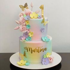 a multi - tiered cake with flowers and butterflies on the top is decorated in pastel colors