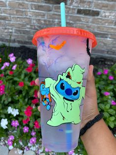 a hand holding up a cup with an image of stitchy on it