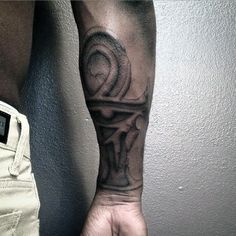 a man's arm with a black and white tattoo design on the left forearm