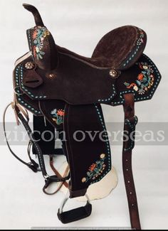 a brown and blue saddle with floral decorations on it's seat, sitting against a white background