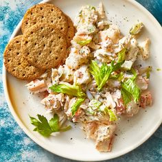 a white plate topped with salad next to a cracker on top of a blue table