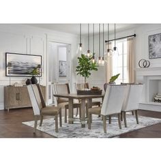 a dining room table with white chairs and a rug on the floor in front of it