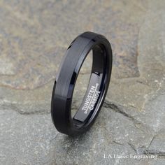 a black ceramic ring sitting on top of a stone slab with the words, i love you