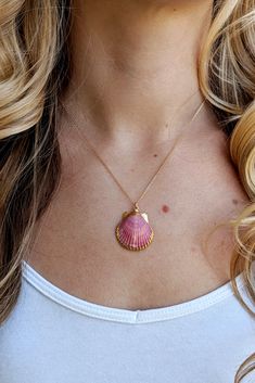 a woman wearing a necklace with a shell on it