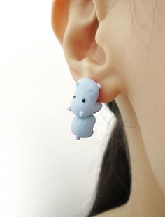 a close up of a person's ear with a small animal dangling from it