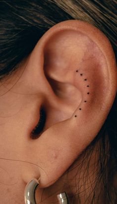 a woman's ear with tiny black dots on it