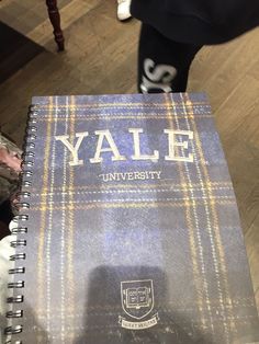 a book that is sitting on top of a wooden table next to a person standing in the background