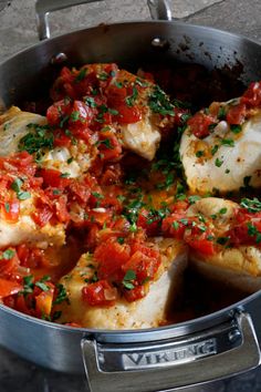 fish with tomatoes and herbs cooking in a pan