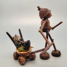 two figurines made out of pine cones and branches with one holding a knife