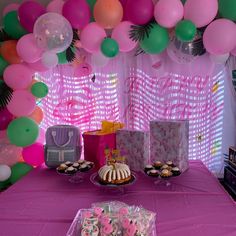 a table topped with lots of pink and green desserts next to a purple table cloth