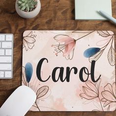 a mouse pad with the word carol on it next to a computer keyboard and plant