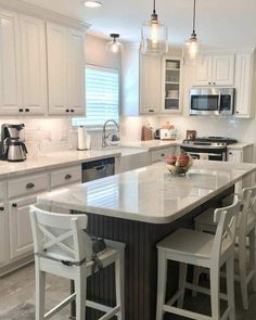 a large kitchen with white cabinets and marble counter tops, an island in the middle