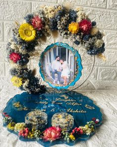 a couple is sitting in front of a blue plaque with flowers on it and the frame has an image of them