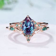 an engagement ring with a blue and green stone in the center, on top of a white surface