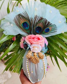 there is a vase with flowers and peacock feathers on it in the palm tree leaves