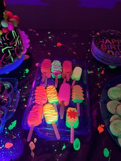 a table topped with cake pops covered in neon colored frosting