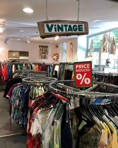 a clothing store with clothes hanging from the ceiling and a price sign in front of it