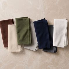 five different colored towels are lined up on the counter top, with one folded in half