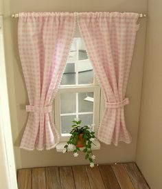 a window with pink gingham curtains and flowers in front of the window sill