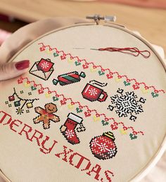 a person holding a cross - stitched christmas ornament