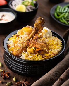 a bowl filled with rice and chicken on top of a table next to bowls of vegetables