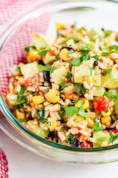 a glass bowl filled with salad on top of a red and white checkered table cloth