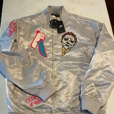 a silver jacket with patches on it and a tag hanging from the back, sitting on top of a counter