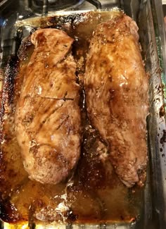 two pieces of meat sitting in a glass dish