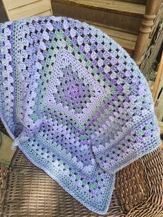 a crocheted blanket sitting on top of a wicker chair