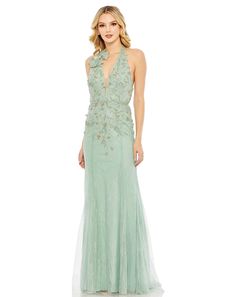 a woman in a long green dress with an open back and floral appliques