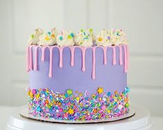 a purple cake with sprinkles and white frosting