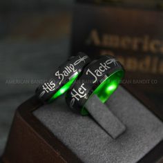 two black and green rings with white lettering on them sitting on top of a wooden stand