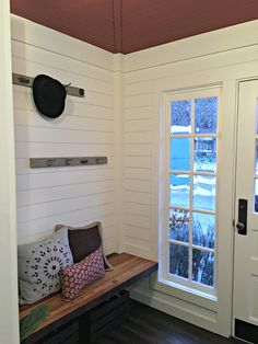 a wooden bench sitting in front of a window on top of a hard wood floor