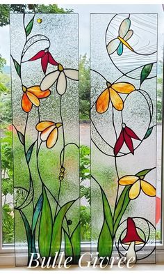 two stained glass panels with flowers and leaves on them in front of a window sill