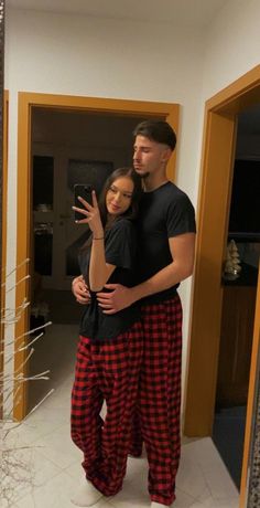 a man and woman are taking a selfie in the mirror while wearing matching pajamas